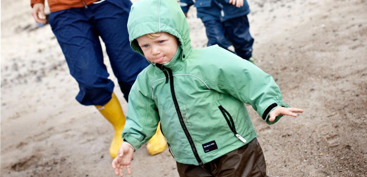 Familie på strand i regntøj